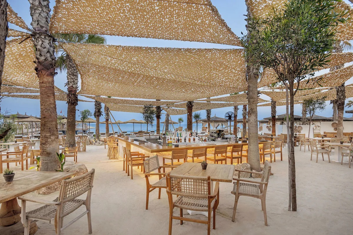 Cullinan Belek plaj restoranında gölgelikler altında ahşap masa ve sandalyeler