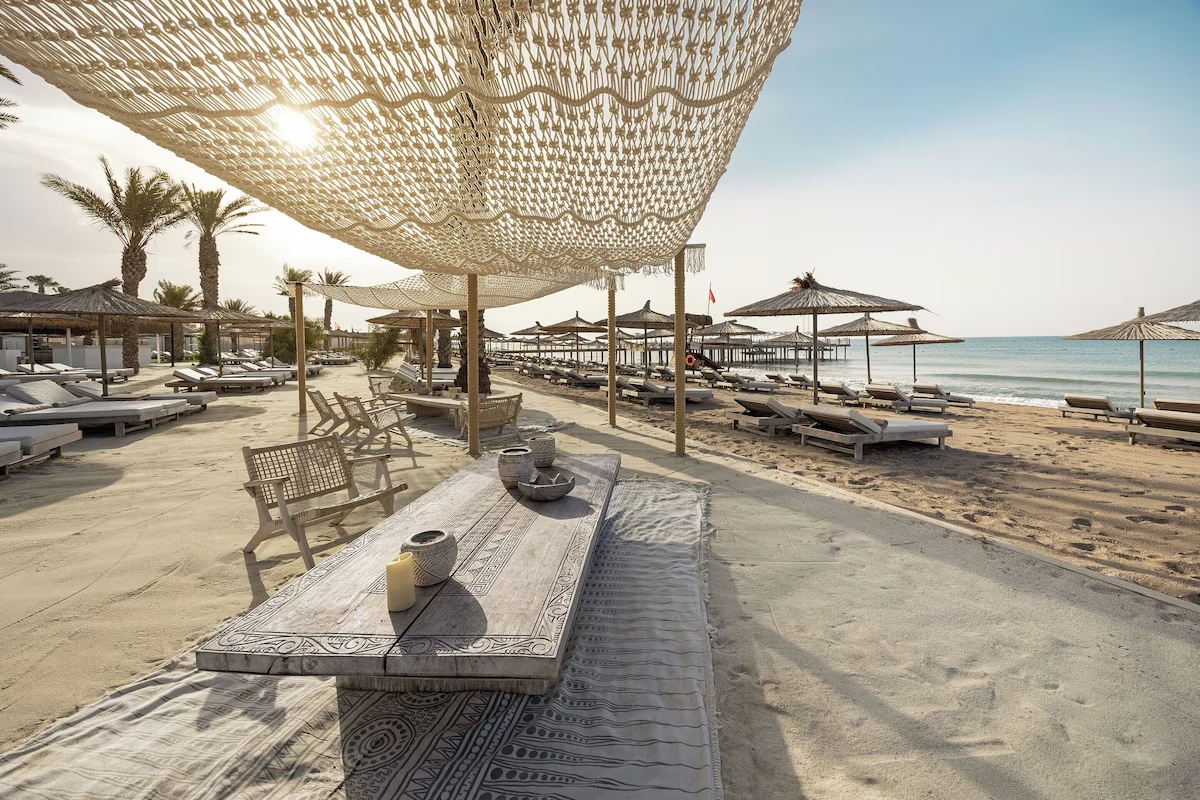 Cullinan Belek plajında gölgelikler, ahşap bank ve şezlonglar