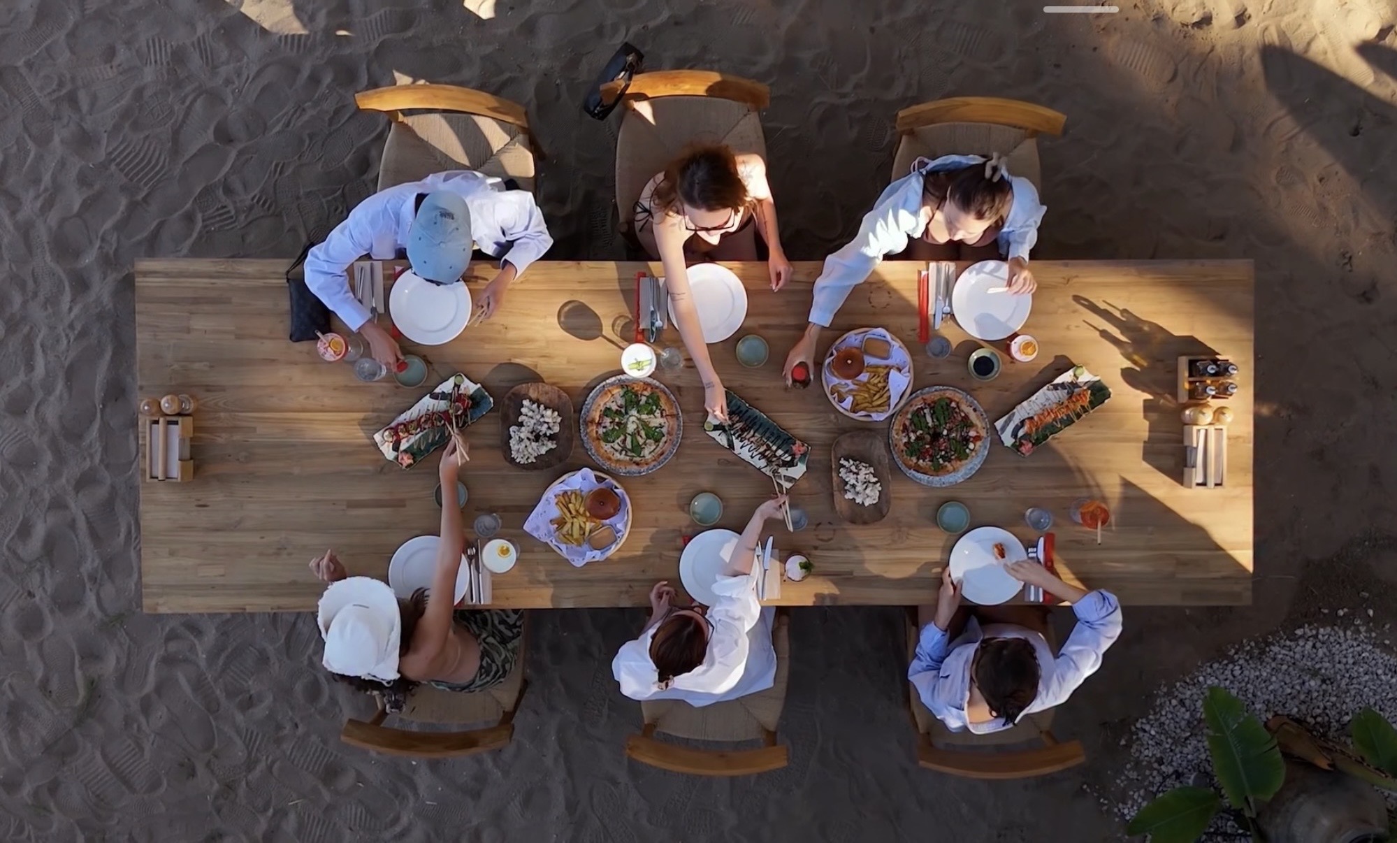 Qualista Beach Antalya kumsalında uzun ahşap masada yemek yiyen misafirlerin yukarıdan görünümü