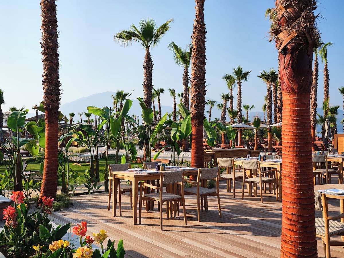 Cape Arna XO Fethiye açık hava restoranında ahşap masa ve sandalyeler