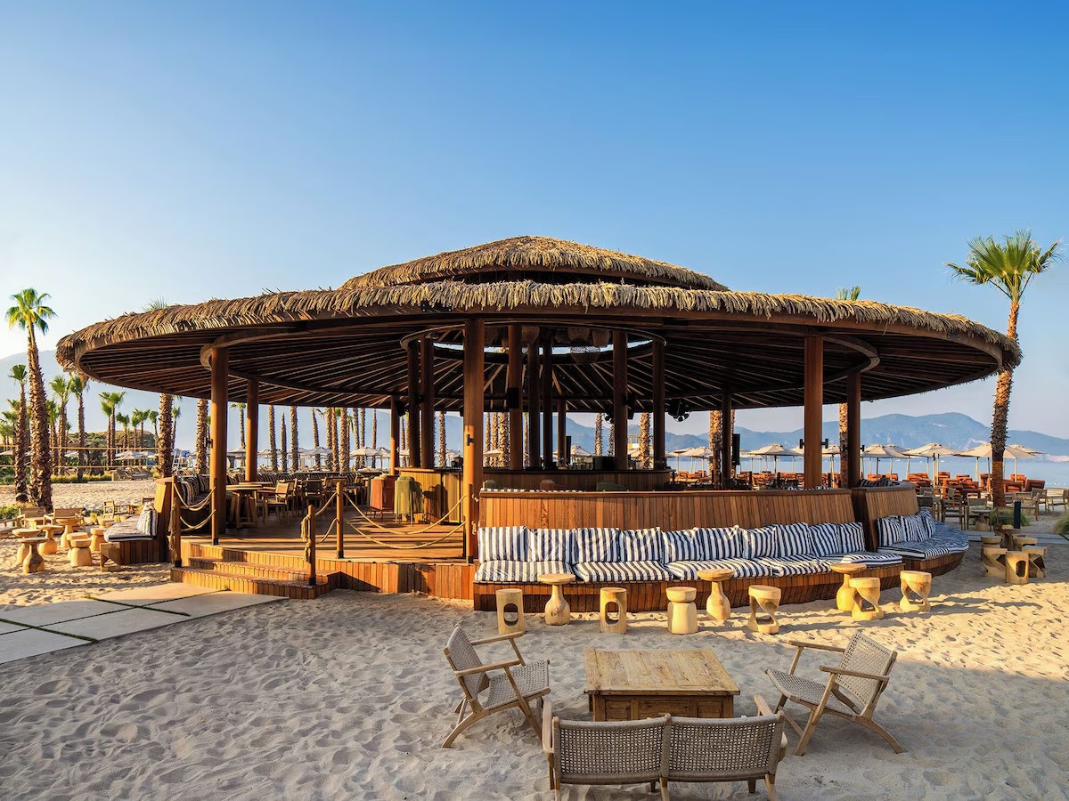 Cape Arna XO Fethiye plajında hasır çatılı bar ve oturma alanı