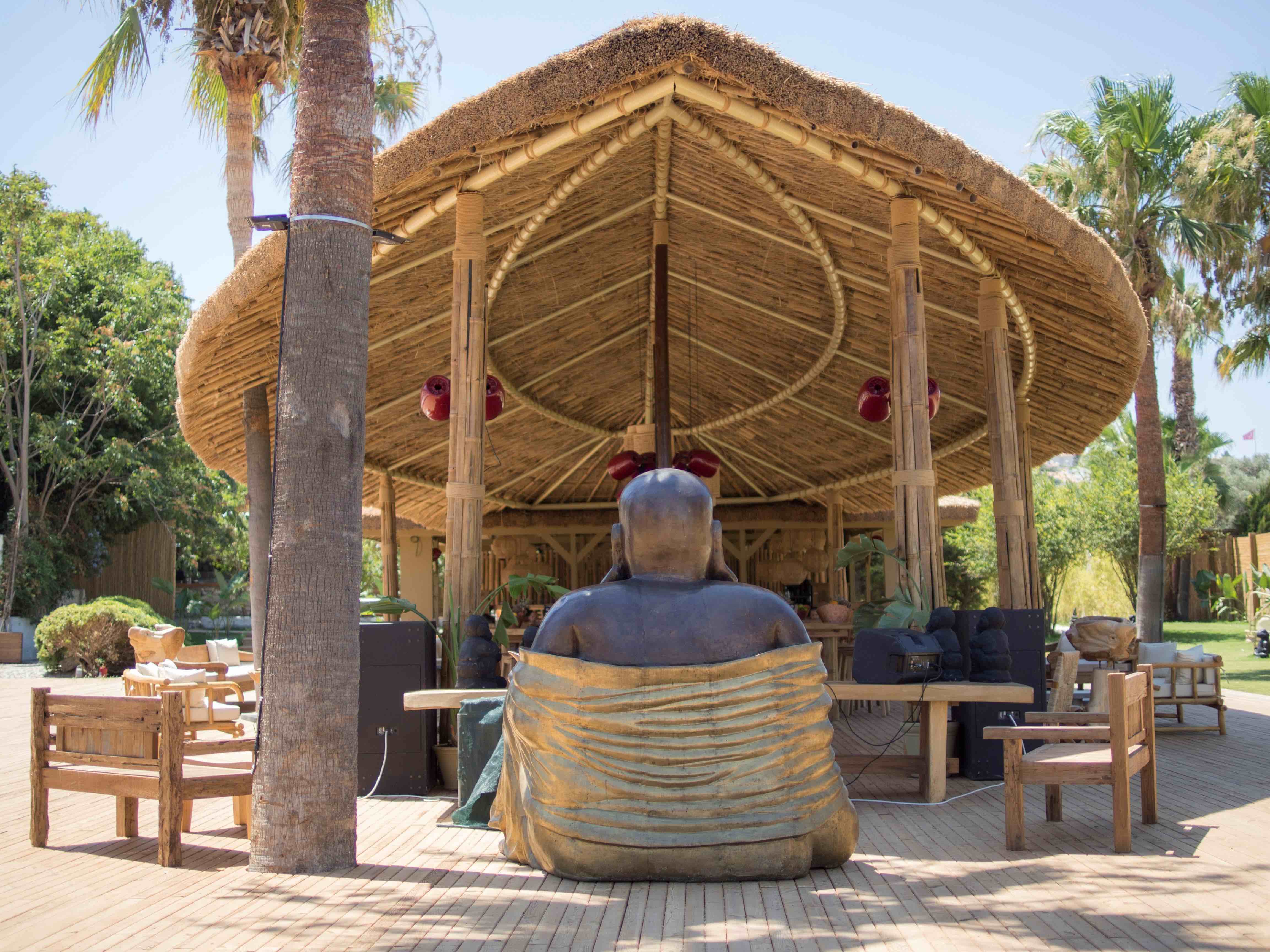 YUZU Beach Çeşme'de bambu çatılı köşk, Buda heykeli ve ahşap oturma grupları